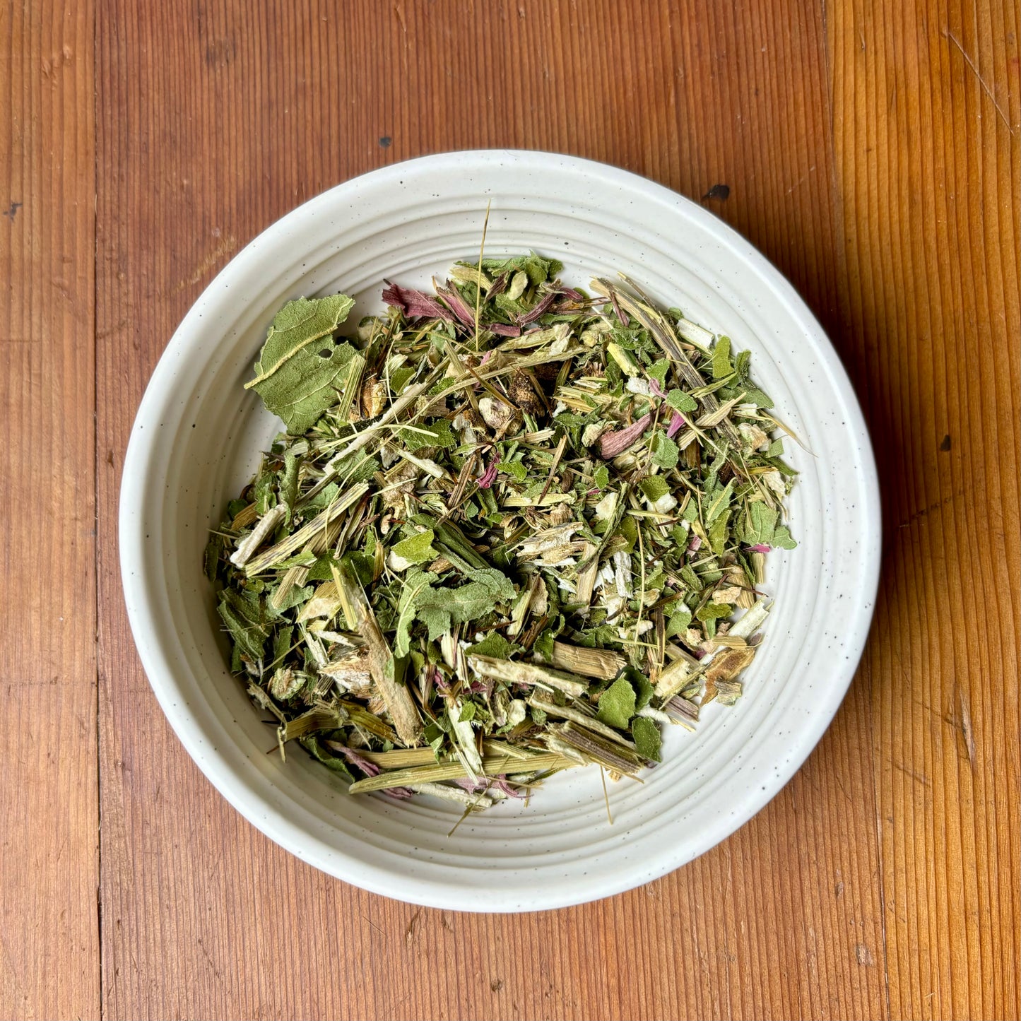loose boost herbal tea in a white bowl on a wooden background