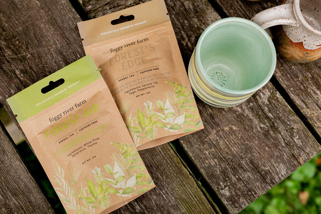 foggy river forest air and forest's edge tea laid on a picnic table alongside two pottery mugs